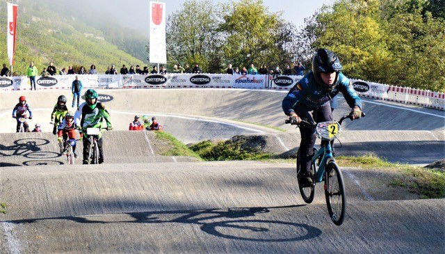 Ein Junge mit Helm auf einem BMX-Rad springt über einen Hügel.