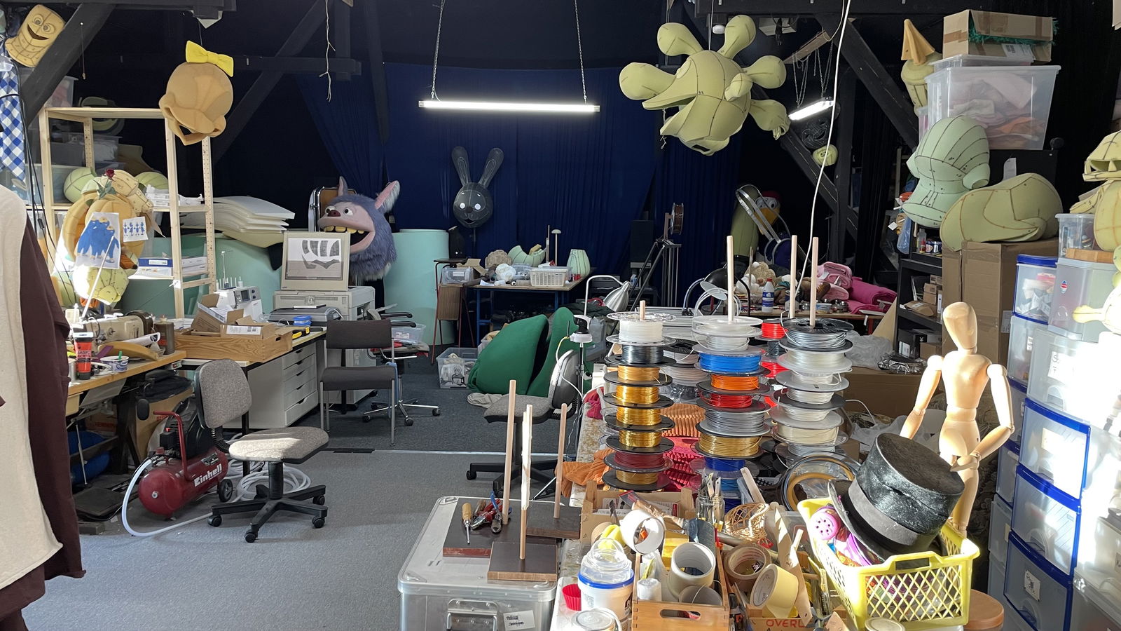 Ein Raum mit vielen Puppen, Stoffen und Nähwerkzeug