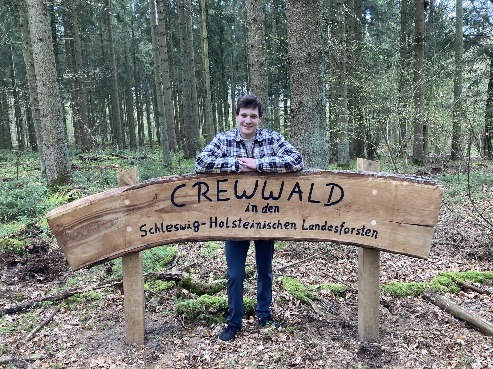 Wincent Weiss hinter dem Crewwald-Schild im Wald