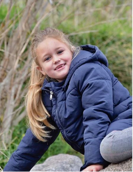 Ein blondes Mädchen mit Zahnlücke lacht in die Kamera.