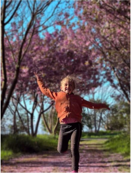 Ein blondes Mädchen läuft strahlend über einen Feldweg.