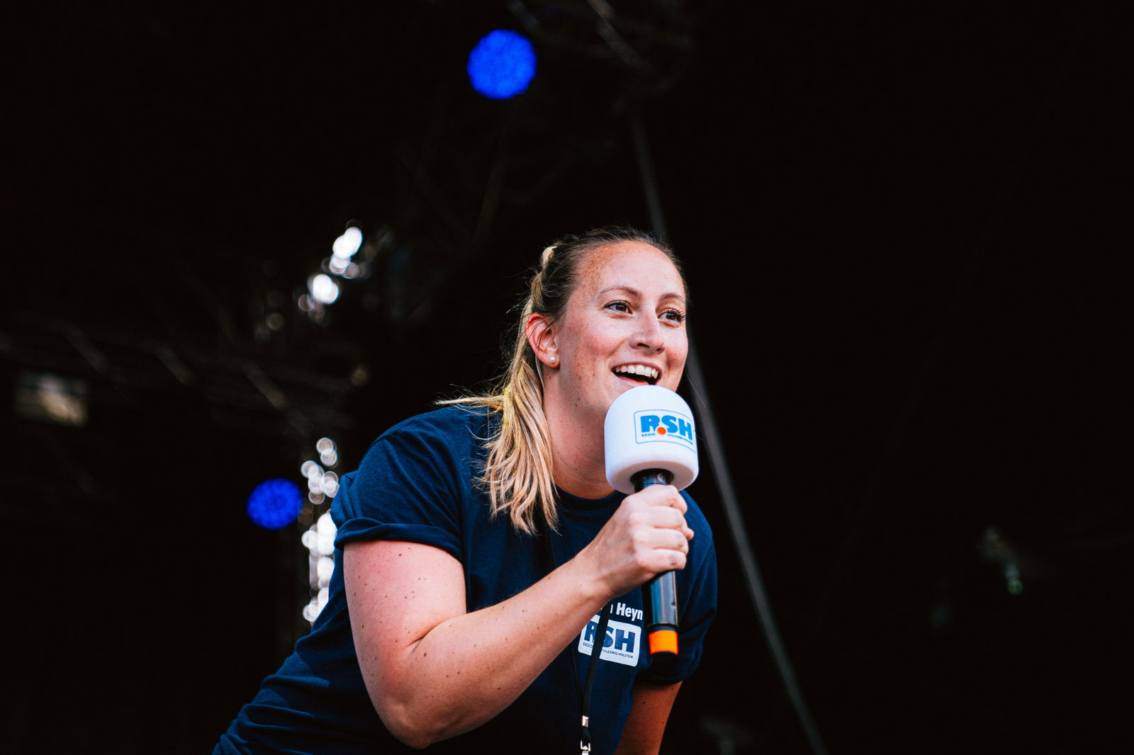 Sharon Heyn steht auf einer Bühne und hält ein Mikrofon in der Hand