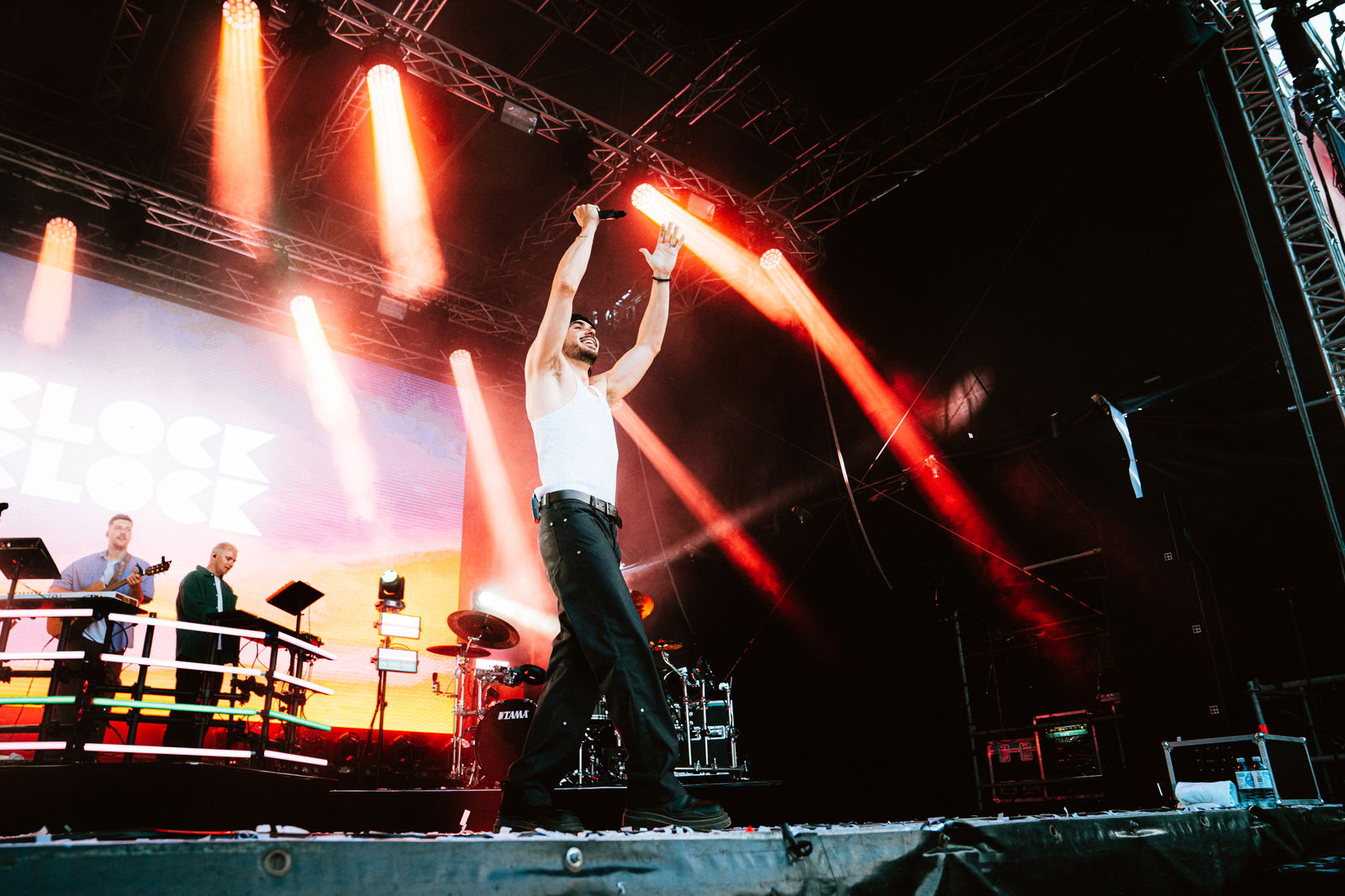 Ein Mann steht auf einer Bühne und hält beide Hände in die Luft