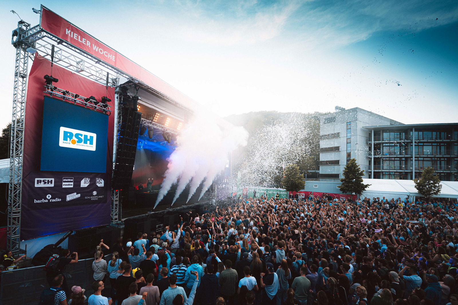 Menschen bei einem großen Konzert strecken die Hände in die Luft.