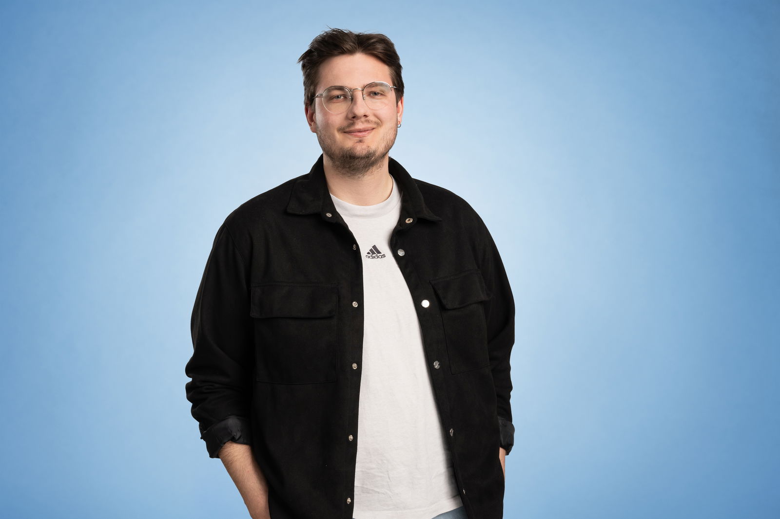 Colin Mock steht vor einem blauen Hintergrund und lächelt in die Kamera